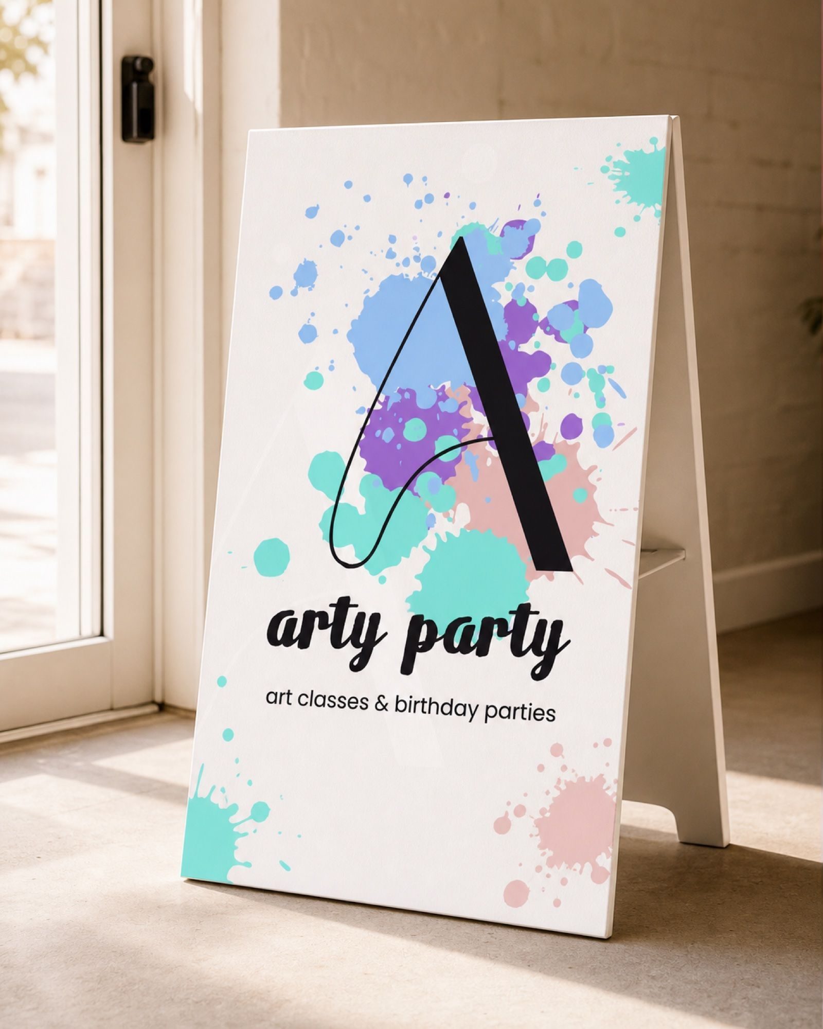 The A-frame sidewalk sign by the studio door, the same tagline as the card sized up for foot traffic.