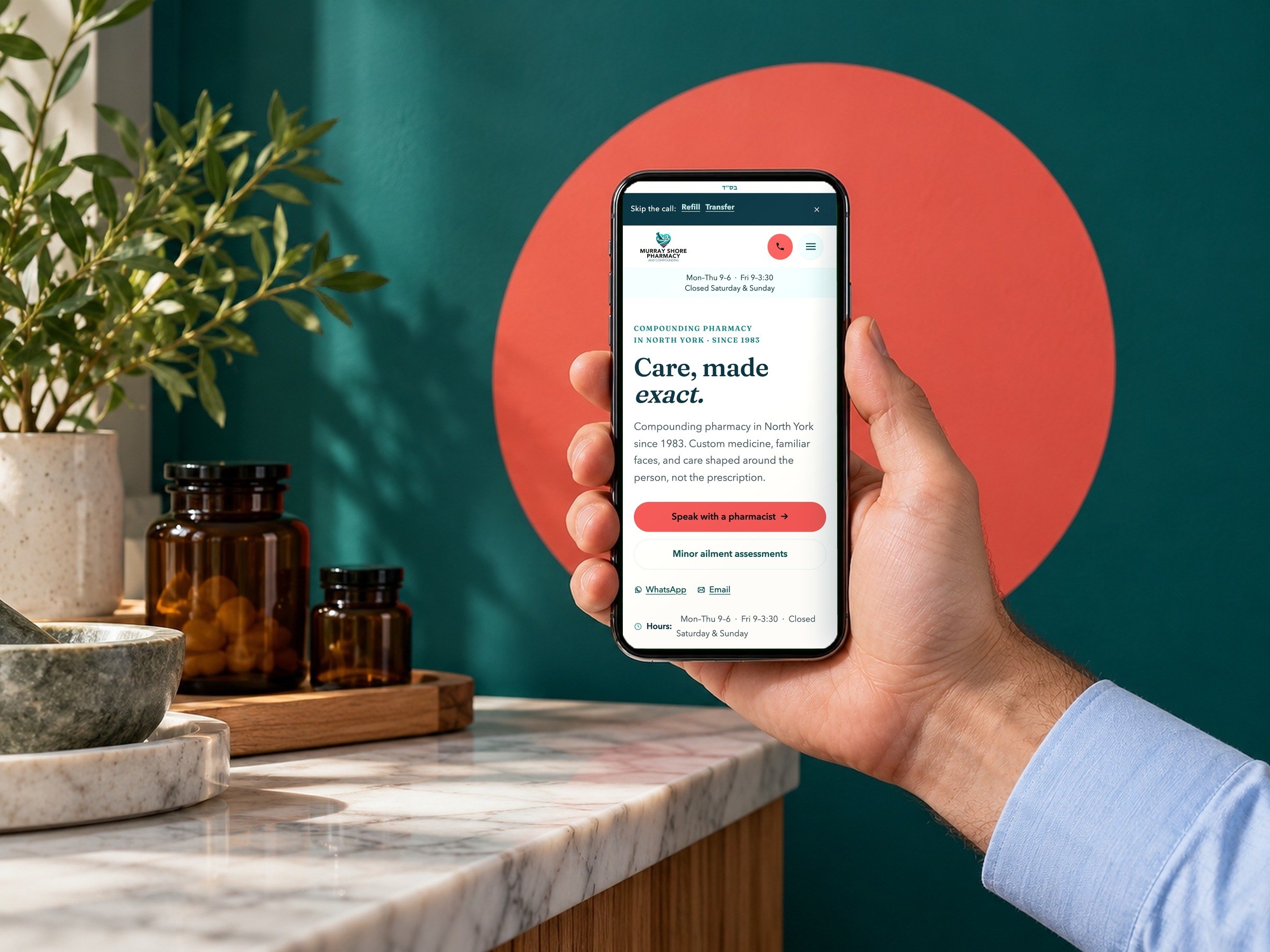 The murrayshore.com home page on a phone, held up against a teal wall with a coral circle.