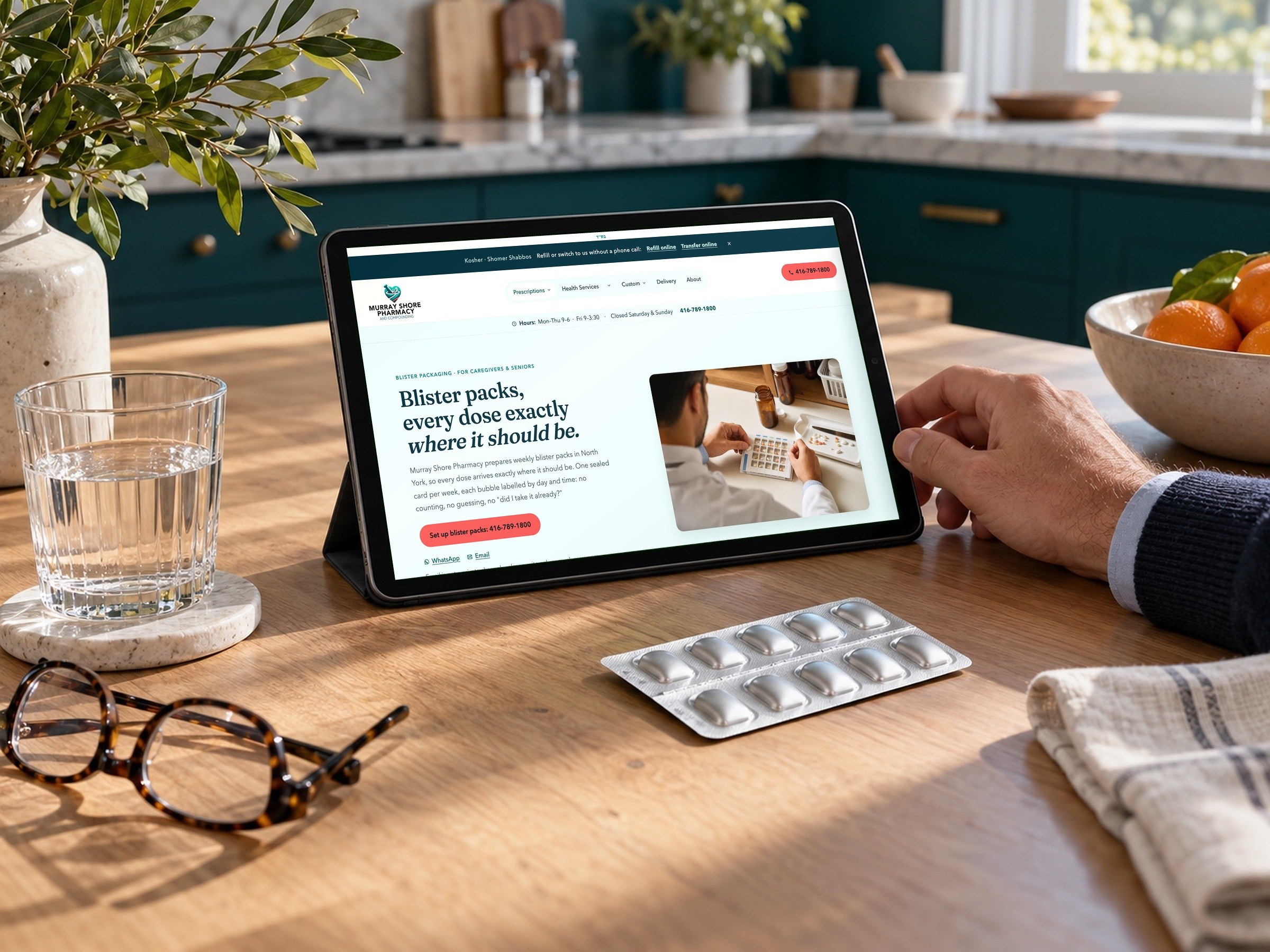 The blister packs page on a tablet at a kitchen table, beside a weekly pack.